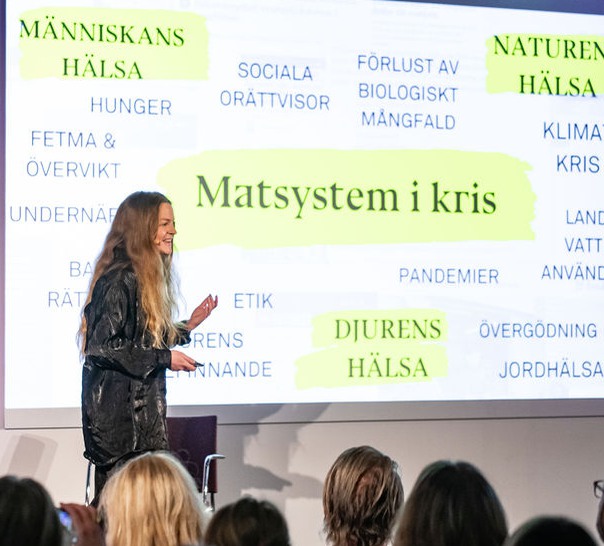 Bild på talare framför publik.