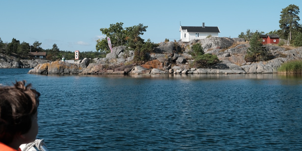 Skärgårdsvy från båt med ö och vitt hus i fronten