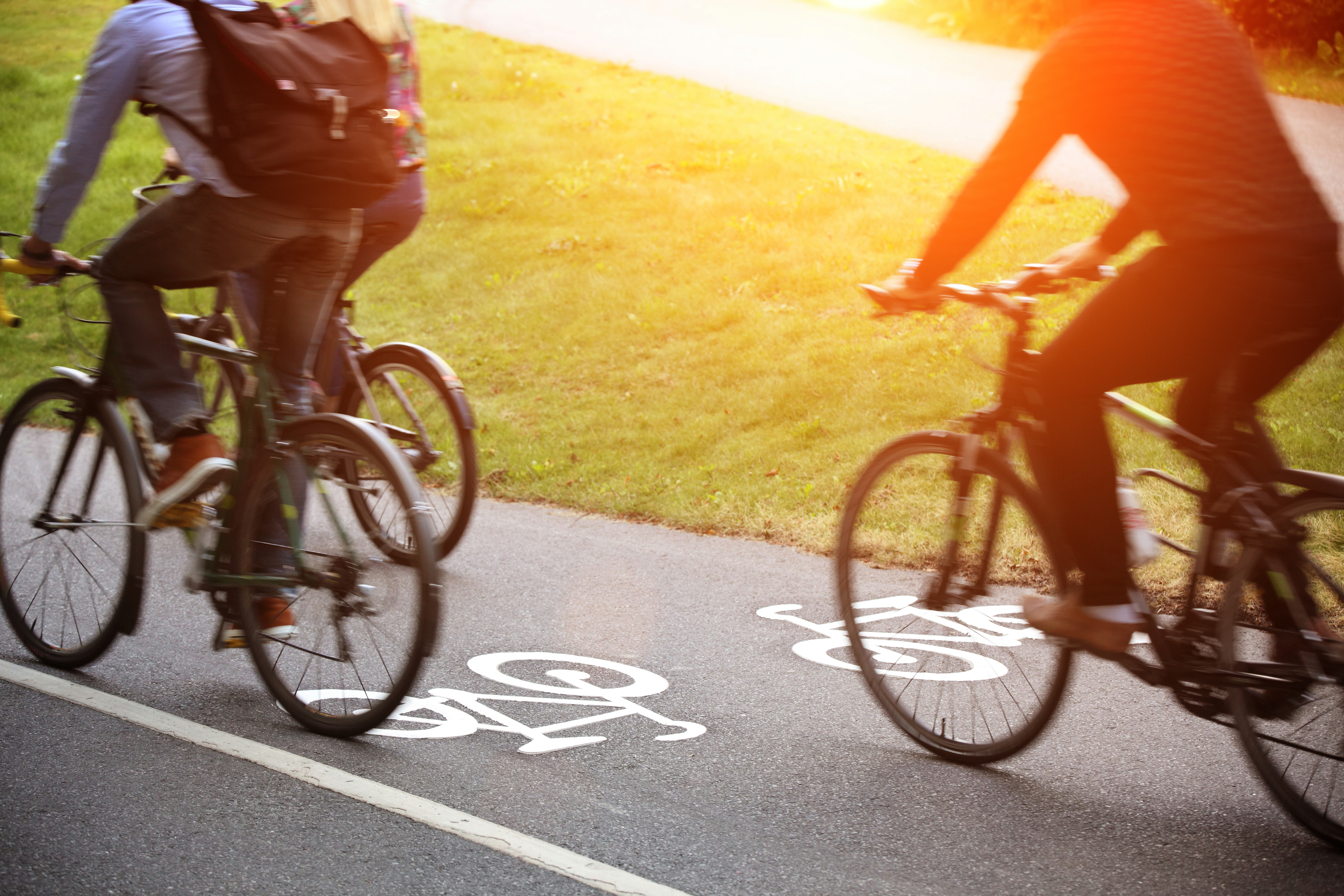 Cyklister i solnedgång på en asfalterad cykelbana.