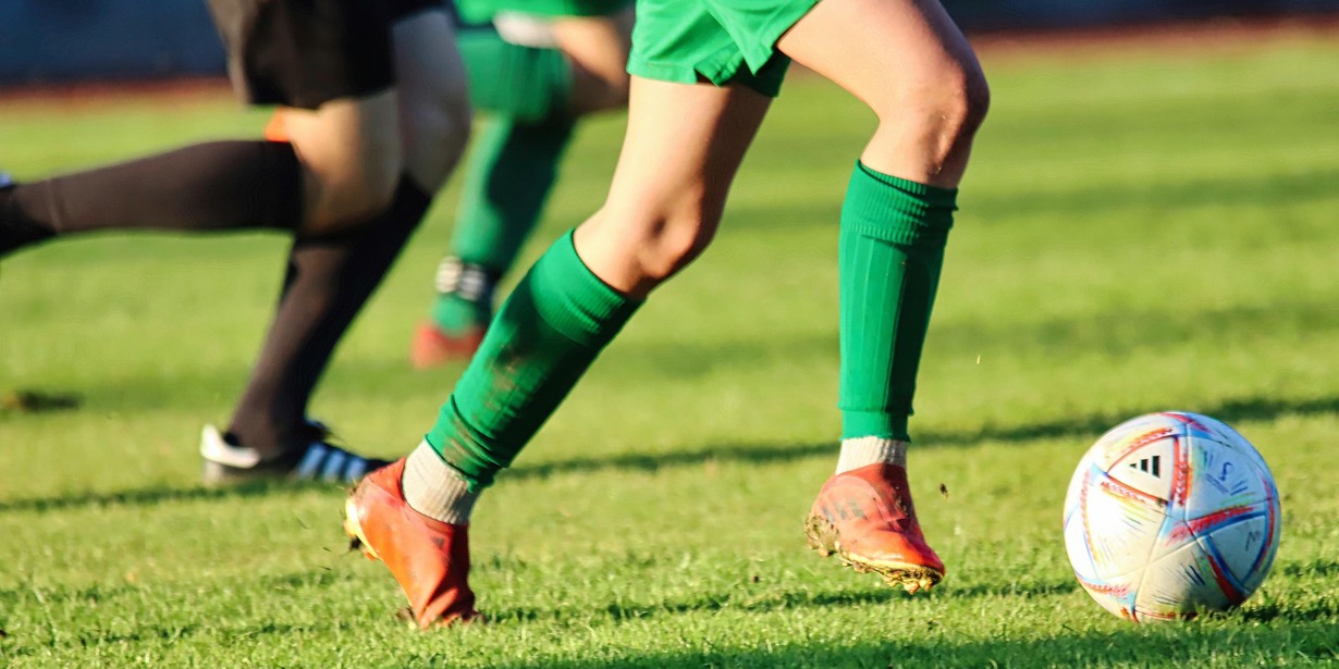 Personer spelar fotboll på gräsplan.
