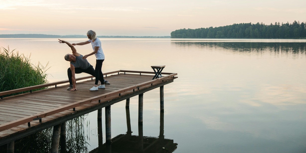 Personer gör yoga på brygga över stilla vatten. 