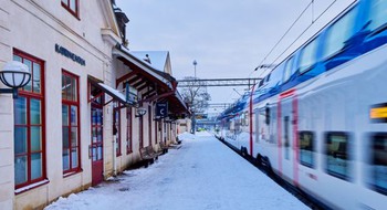 Ett tåg som passerar en byggnad en snöig dag.