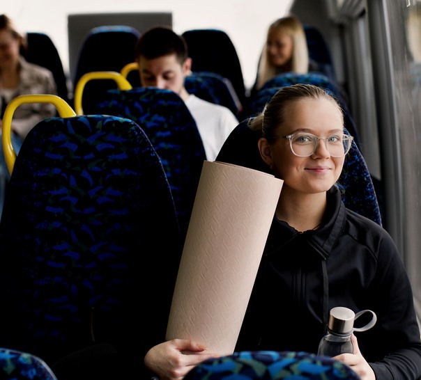 Kvinna sitter med yogamatta och vattenflaska på bussen.