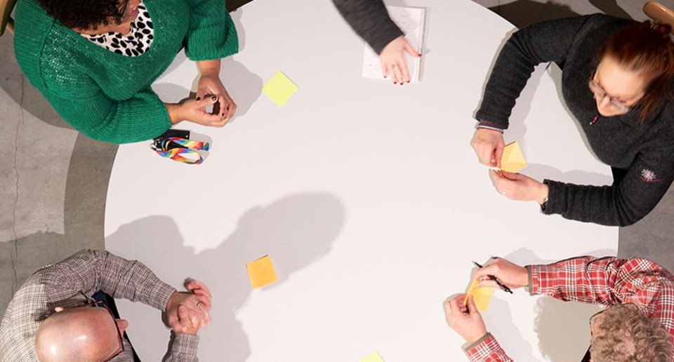 Personer sitter runt ett bord och diskuterar