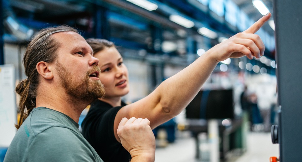 En kille och en tjej framför ett elskåp i en industrihall