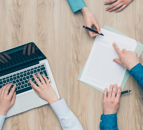 Tre personers händer på arbetsbord under ett arbetsmöte