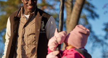 Pappa gungar sitt barn i en lekpark. 