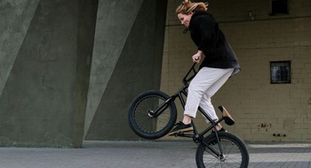 En cyklist hoppar med cykeln på asfalt.