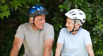 Två person på cyklar med grönska runt om. 