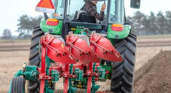 Traktor som plöjer en åker, vilket illustrerar arbete inom de gröna näringarna.