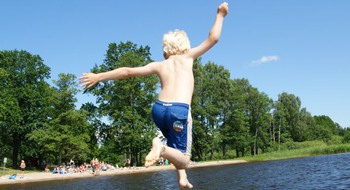 Pojke hoppar från en brygga ner i vattnet.