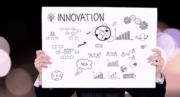 Person håller upp en skylt med ritade symboler där det står "Innovation."