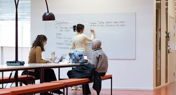 Tre personer grupparbetar i skolan.
