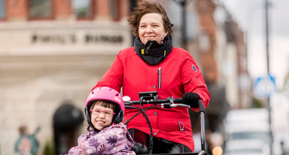 Cyklande mamma med barn i cykellåda.