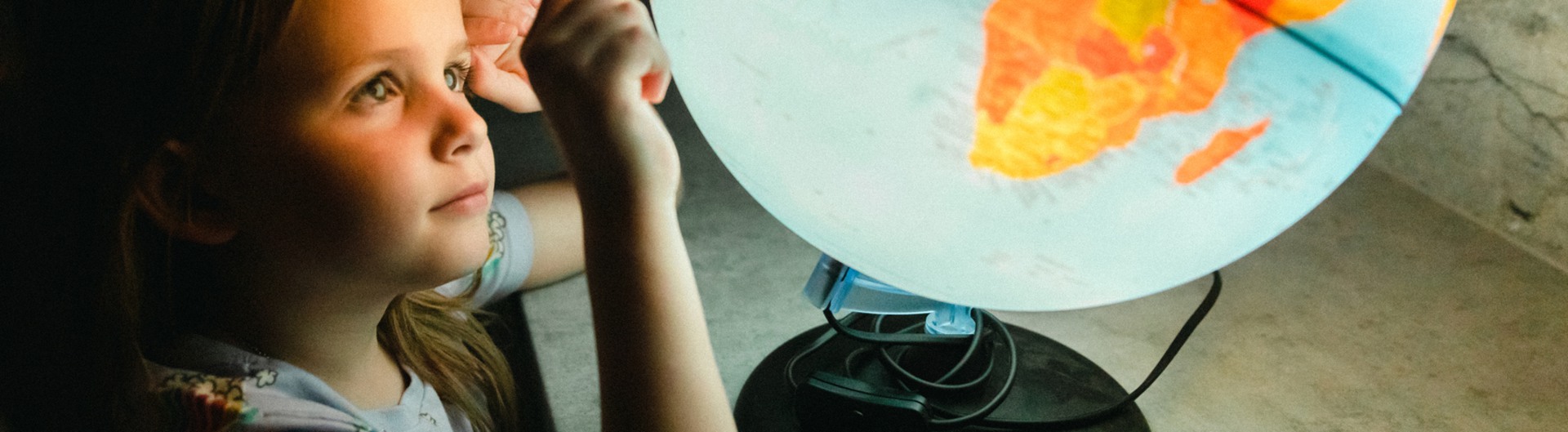 Liten flicka som söker efter land på en lysande jordglob