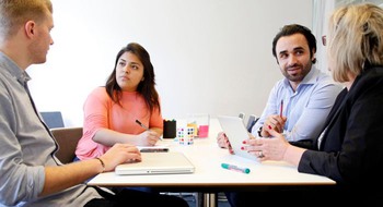 Fyra personer sitter vid ett bord och pratar.