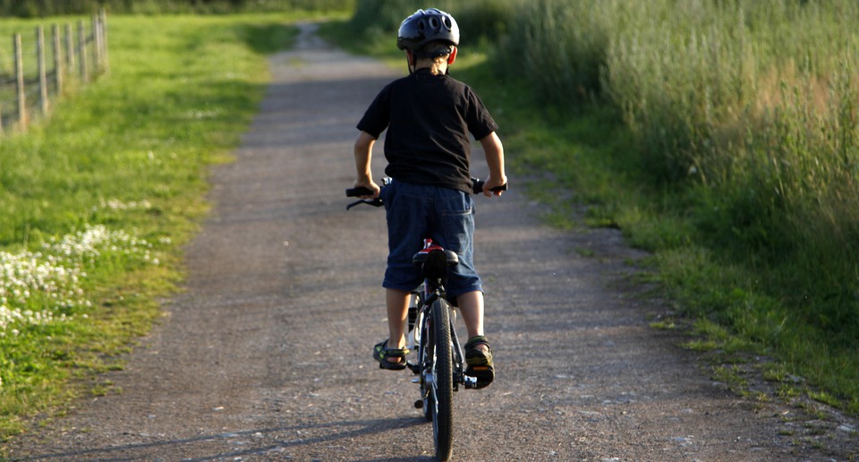 Ett litet barn cyklar på en grusväg.