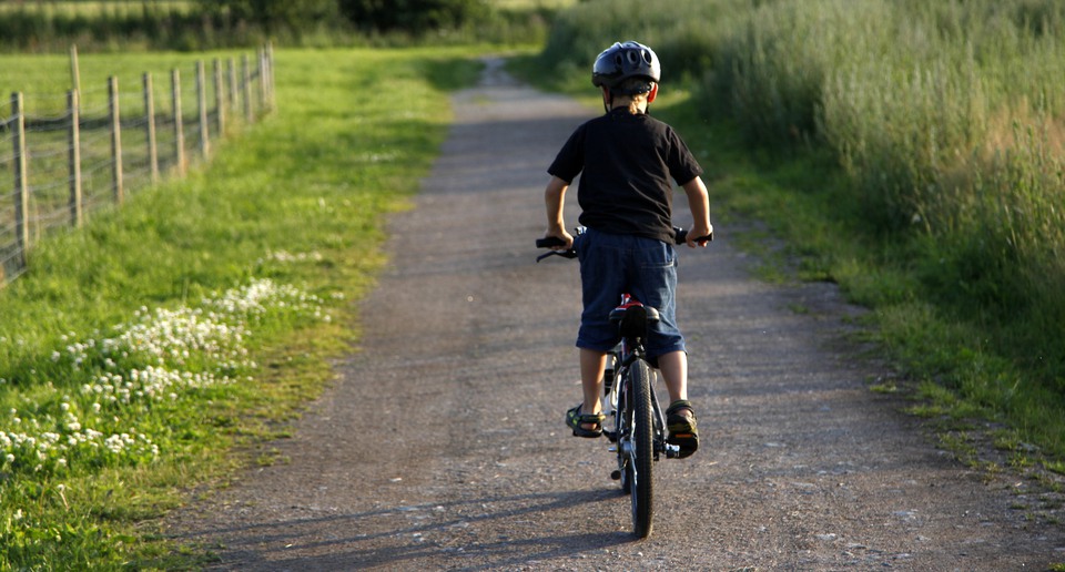 Barn som cyklar på grusväg. 