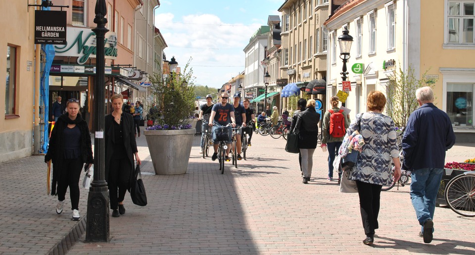 Människor som promenerar och cyklar på en gågata i en småstad.