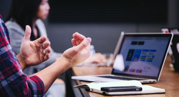 Personer vid skrivbord med dator och mobiltelefon.