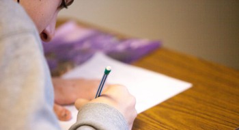 En ungdom som gör noteringar på ett papper.