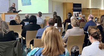 Person talar framför en sittande publik.