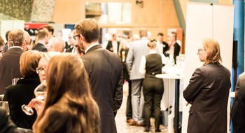 Människor står och minglar i en stor sal.