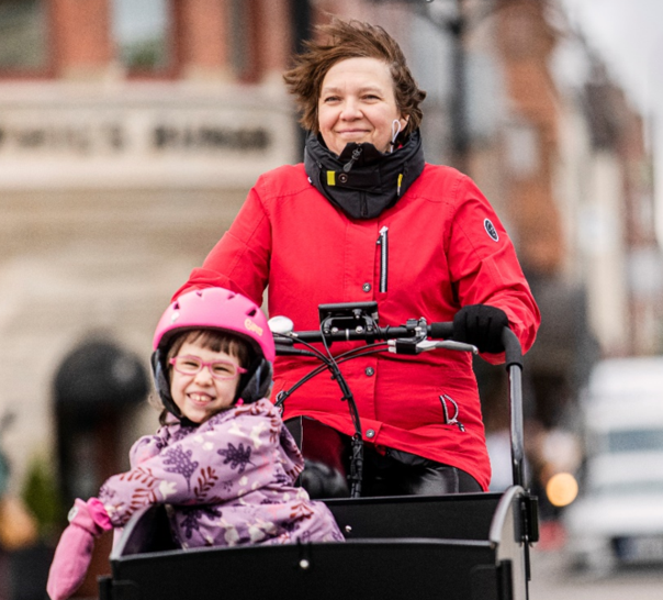 Cyklande mamma med barn i cykellåda.