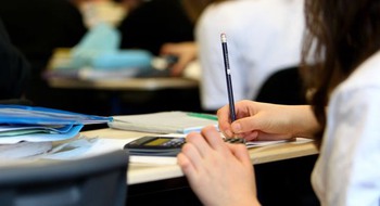 Elever sitter vid bänkar och skriver.