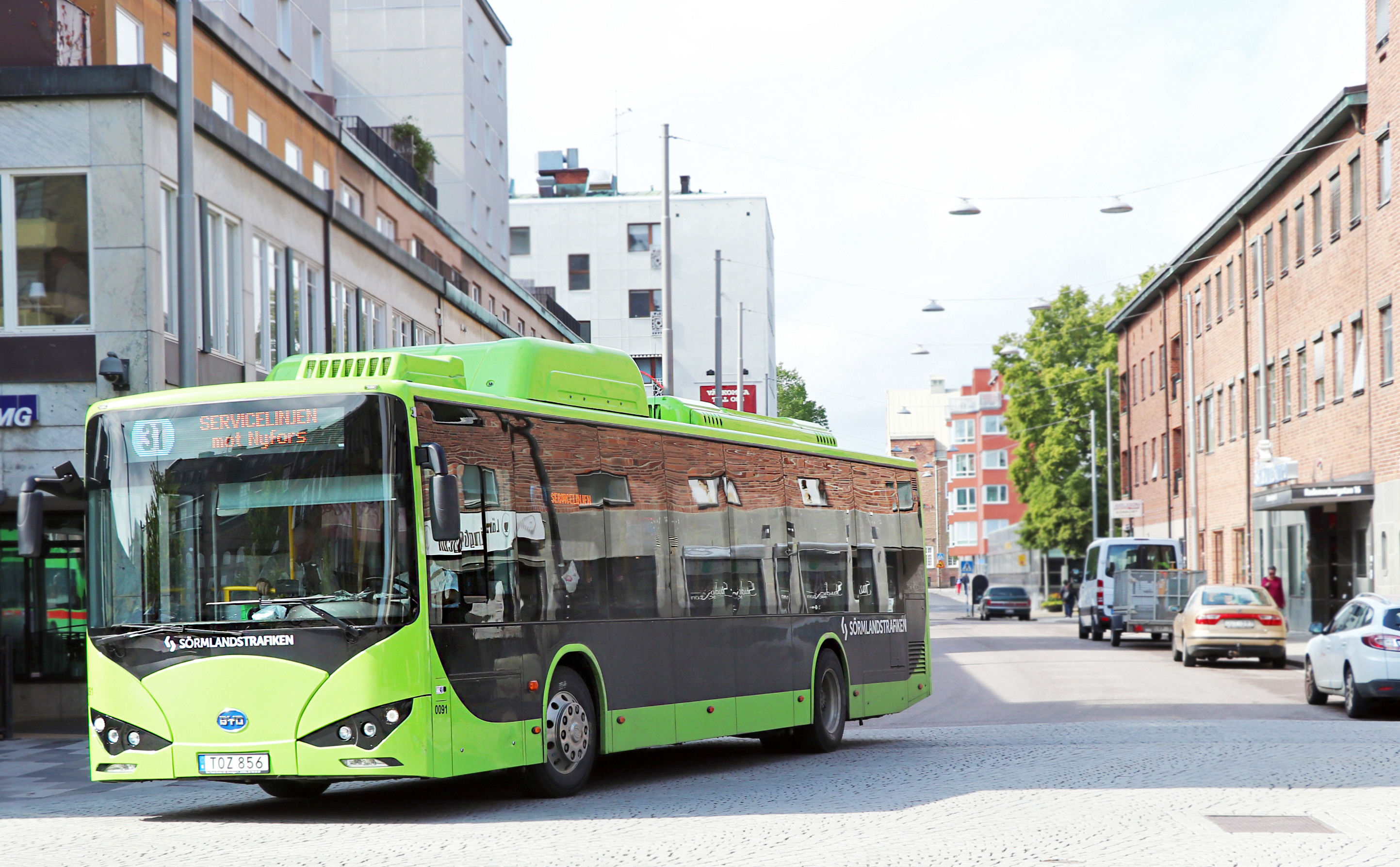 Grön buss på gata i stadsmiljö