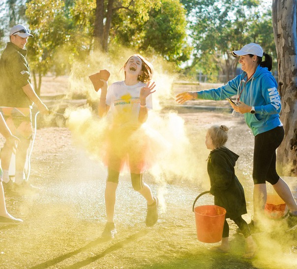 En familj leker utomhus med pulverfärg, solen skiner.
