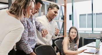 Grupp med människor som diskuterar vid ett skrivbordsarbete.