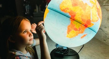 Rosa grafik utan motiv.Liten flicka som söker efter land på en lysande jordglob.