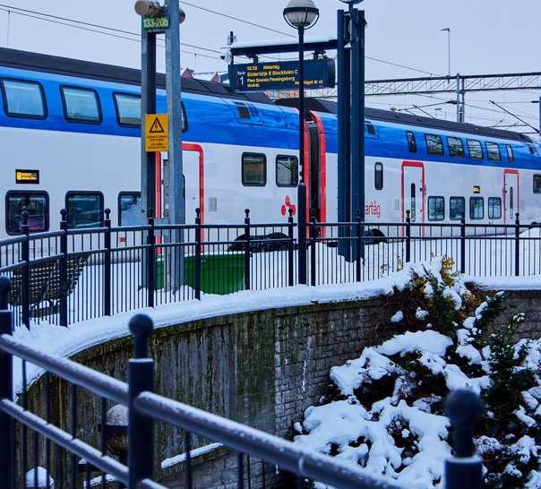 Ett blåvitt tåg som kör in på en tågstation.