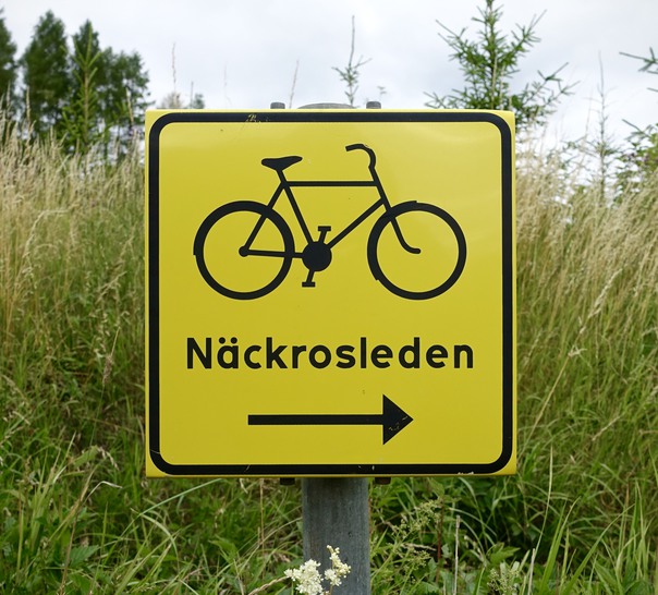 Gul skylt för Näckrosleden med en cykel på. 