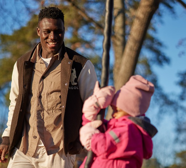 Pappa gungar sitt barn i en lekpark. 