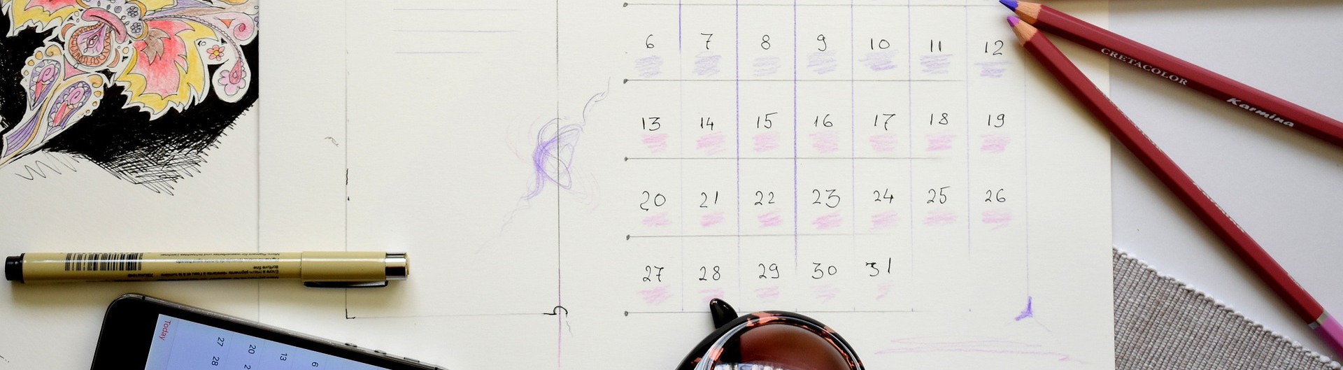 Kalender, mobiltelefoner, pennor och solglasögon på ett bord.