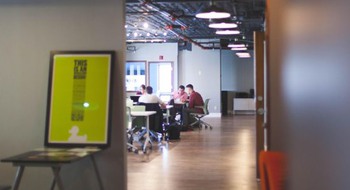 Personer sitter vid skrivbord och arbetar tillsammans. 