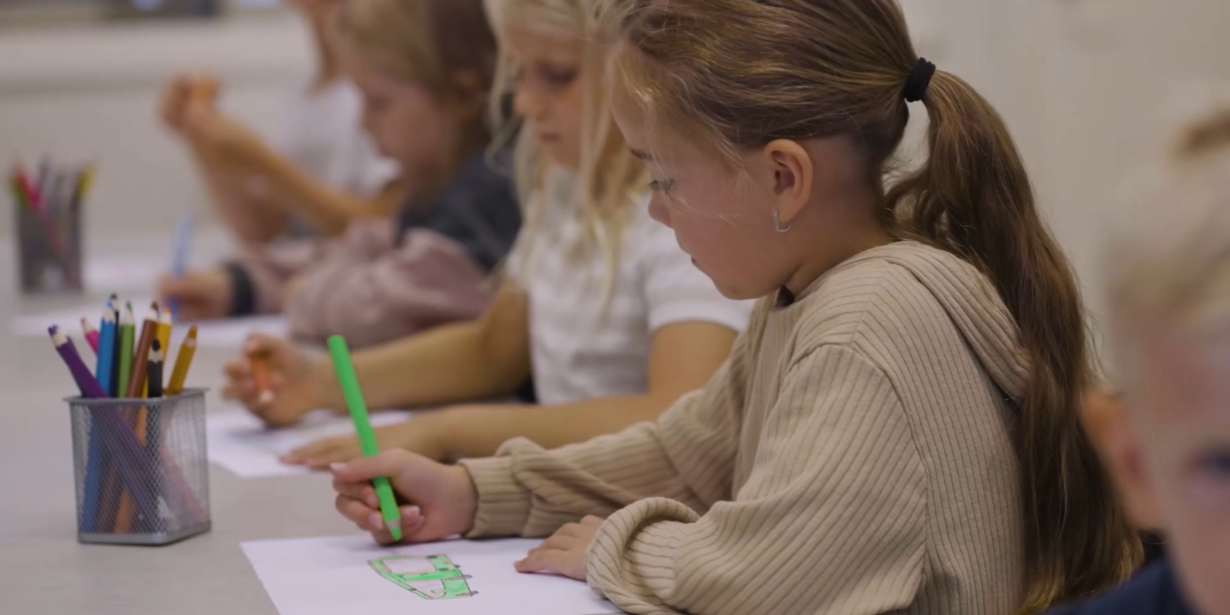 Barn sitter vid bord och ritar.