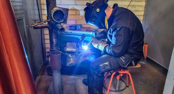 Sittande person som svetsar.