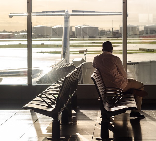 En person sitter på en flygplats med utsikt över ett flygplan.